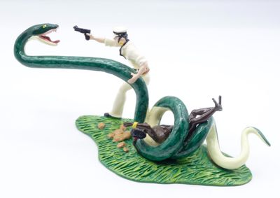 une figurine représentant un homme chevauchant un serpent et tenant un pistolet