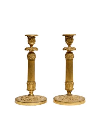 pair of antique brass candlesticks on pedestals on a white background