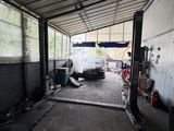 a car parked in a garage with a truck in the background