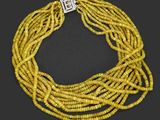 un collier de perles jaunes muni d'un fermoir en argent, sur fond noir