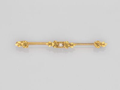 une broche en forme de lingot d'or ornée de fleurs et de feuilles