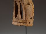 a wooden sculpture of a face on a black stand