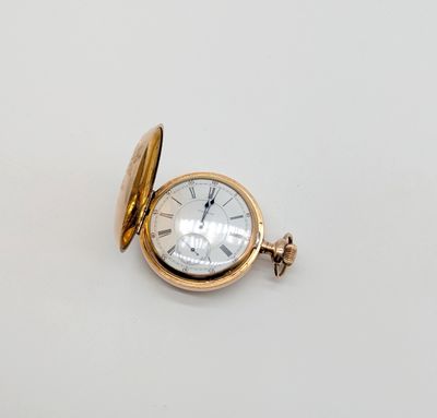 une image d'une montre de poche en or sur une surface blanche