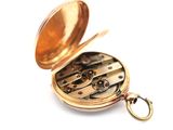 a gold pocket watch that is open on a white surface