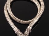 a silver bracelet with a snake head on a black surface