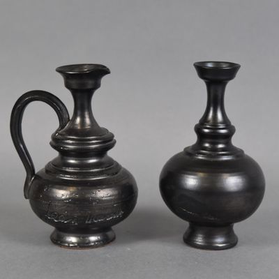 pair of black vases sitting on top of a gray surface