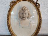 an old picture of a young girl in a blue dress in a gold frame