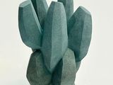 une sculpture verte représentant un cactus sur un fond blanc