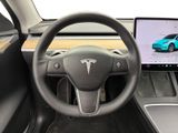 the interior of a tesla vehicle with a laptop on the steering wheel