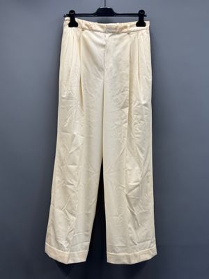 un pantalon blanc suspendu à un cintre devant un mur gris