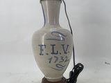 a white vase with blue writing on it sitting on a wooden base