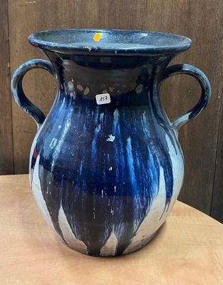 un vase bleu posé sur une table, avec une étiquette dessus