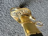 a close up of a gold colored walking stick with a black handle