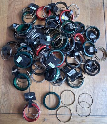 un tas de bracelets de toutes sortes posés sur un plancher en bois