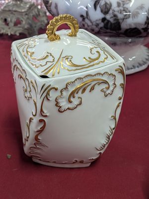 une boîte blanche et dorée posée sur une table rouge