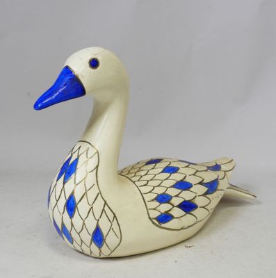 une figurine de canard bleue et blanche posée sur une surface blanche