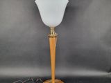 une lampe avec un pied en bois et un abat-jour en verre blanc