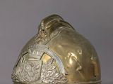 brass fireman ' s helmet on a grey background