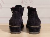 the back view of a pair of purple sued ankle boots on a wooden table