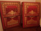 une paire de livres anciens peints en rouge et or, posés sur une étagère en bois