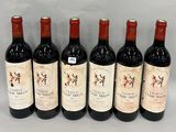 six bottles of red wine lined up in a row on a table