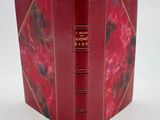 un vieux livre à la couverture rouge posé sur une table blanche