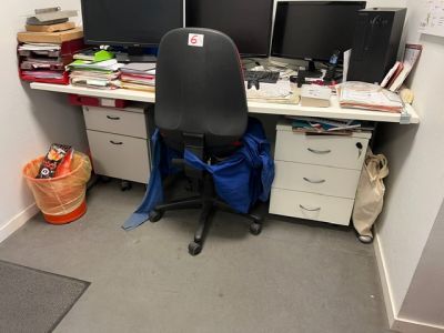 un bureau avec deux écrans d'ordinateur et une chaise dans un coin