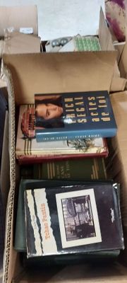 de nombreux livres dans une boîte en carton posée sur le sol