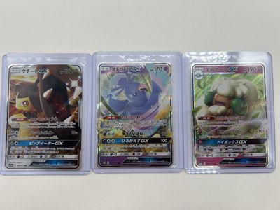 three pokemon cards in plastic cases on a table