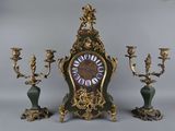 une horloge posée sur une table, avec trois bougies
