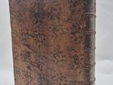 an old book with a brown cover sitting on top of a white surface