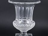 un vase en verre transparent posé sur un socle, sur fond noir