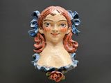 une tête de femme en céramique, avec une rose dans les cheveux