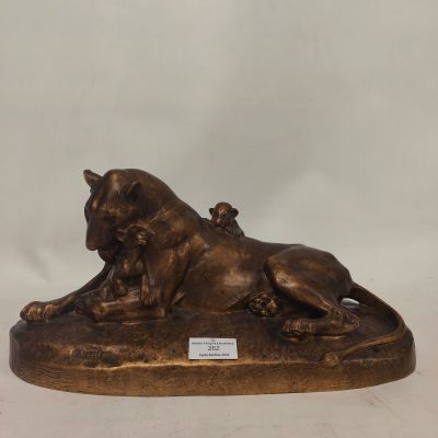 a bronze statue of a lion laying down on a rock