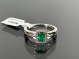 a close up of a diamond and emerald ring on a table