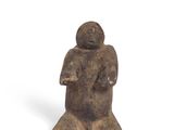 an old figurine of a man sitting on a white surface