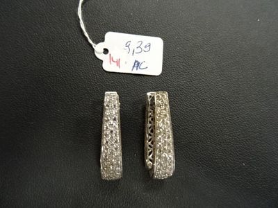 paire de boucles d'oreilles argentées et en cristal, ornées d'étiquettes, sur un fond noir