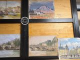 quatre tableaux accrochés au mur d'une pièce où se trouve une horloge