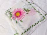 a white sheet with a pink flower and green leaves on it
