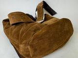 brown sued handbag on white background with black leather strap
