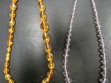 two necklaces of different colors and sizes on a black surface