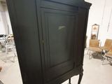 a black cabinet in the middle of a room with chairs in the background