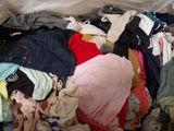a pile of clothes that is sitting on a bed