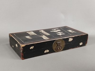 une malle noire munie d'un cadenas, posée sur une surface blanche