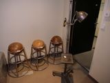 quatre tabourets dans un coin d'une pièce où se trouve une lampe