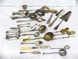 de nombreuses cuillères et couteaux-cuillères en argent posés sur une table