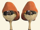 pair of orange high heels with a gold heel and a mirror on the heel
