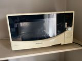 a microwave sitting on a shelf in the corner of a room