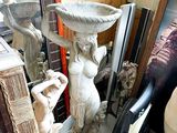 a statue of a woman holding a bowl on top of a table