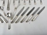 a lot of silver spoons and knives on the table